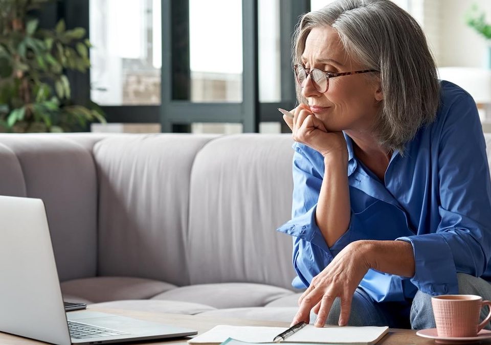 photo of an older women sitting on her couch looking at her computer at retirement resources